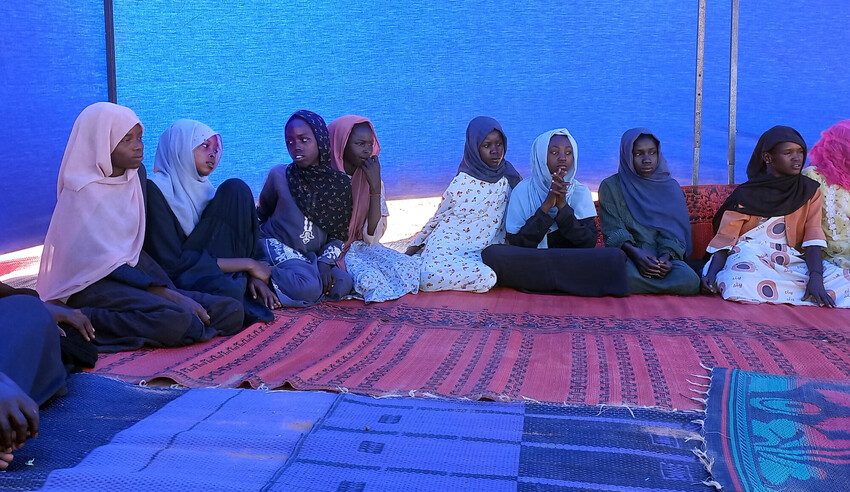 Adolescent girls sit in a semi-circle in the mobile unit. 