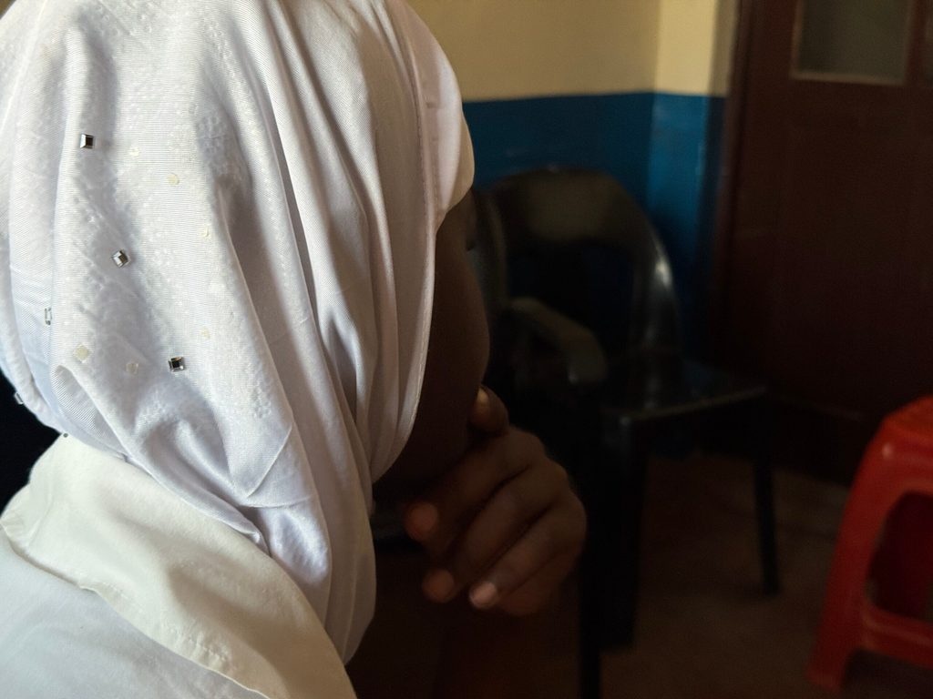 Uma rapariga está sentada de costas para a câmara.