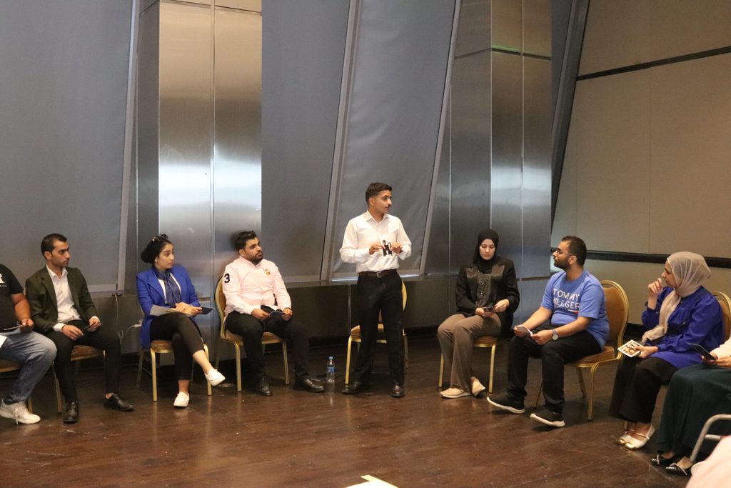 A young male stands to speak at a focus group discussion.