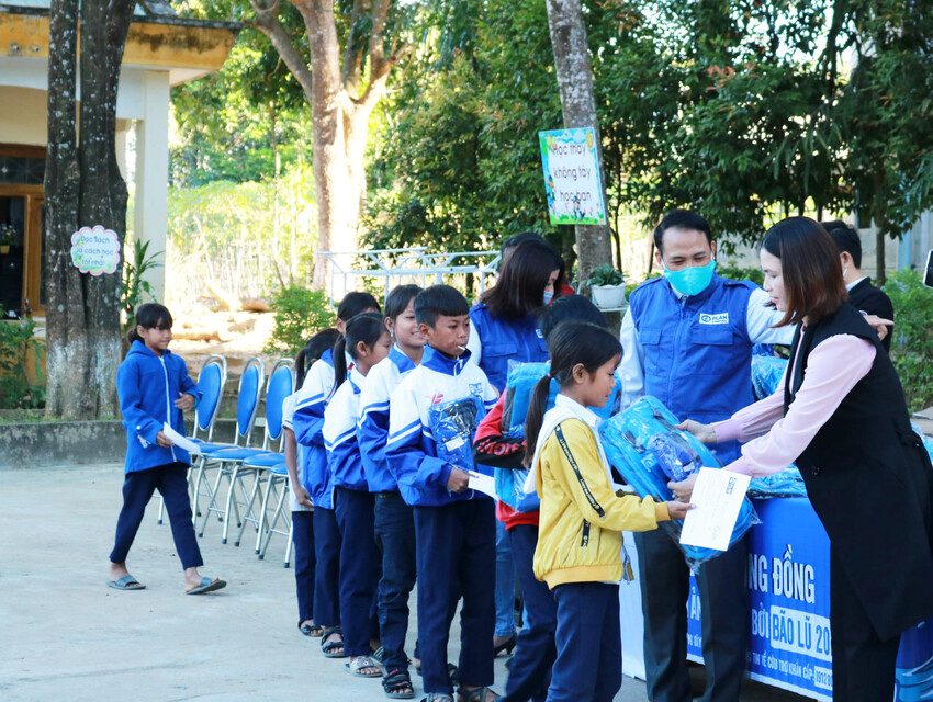 Children receive their new jackets and school bags from Plan International