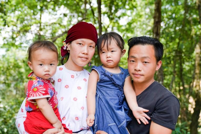 Mai, 21, and her husband and her two daughters outside their house.