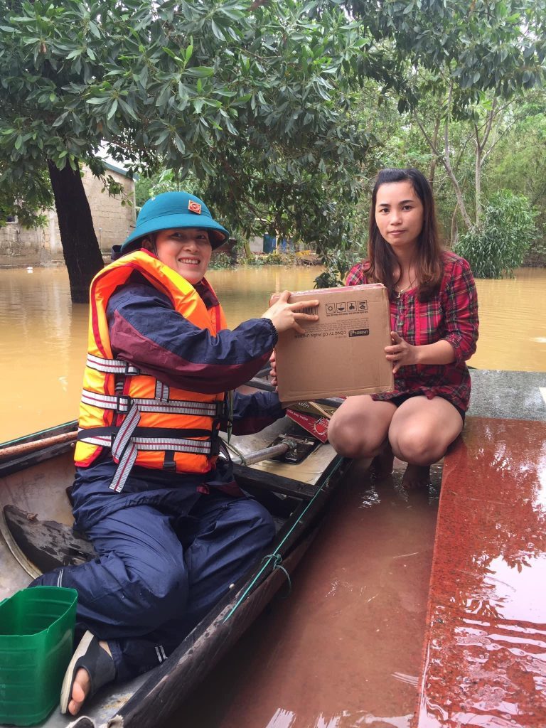 Vietnamese women using a boat to provide food support to isolated households.