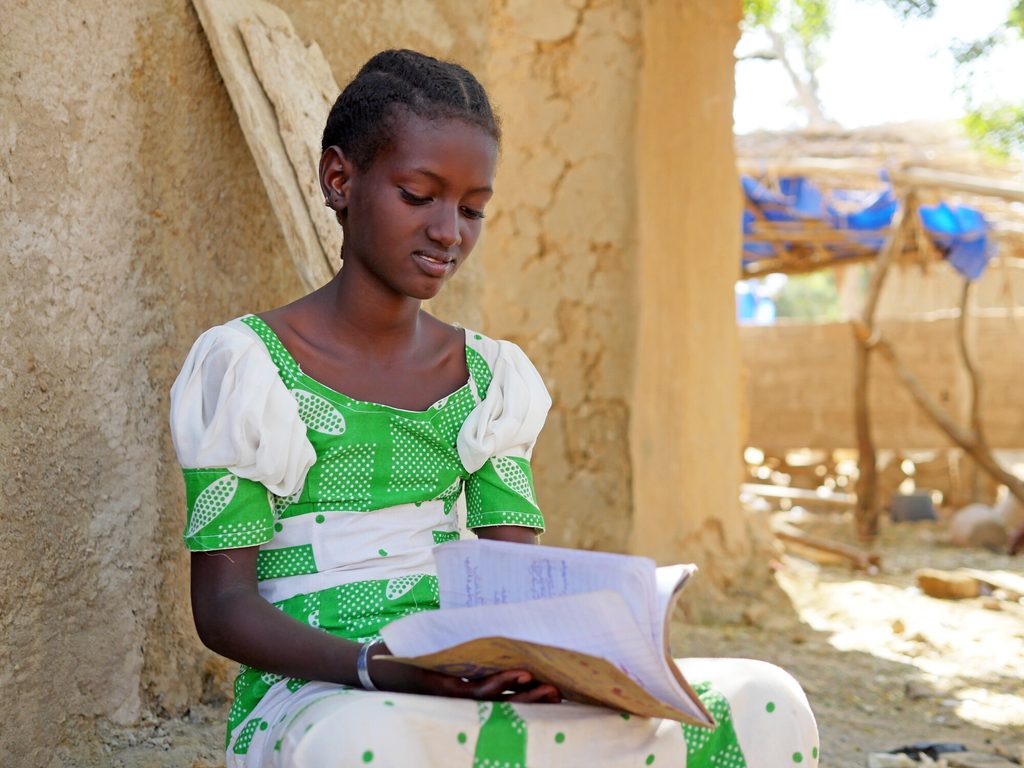 Hawa, 11, flips through her school notebook, smiling.