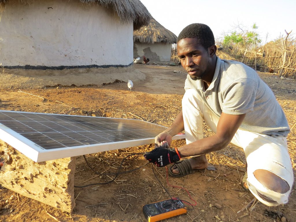 Sidi repairing a solar panel in a rural village