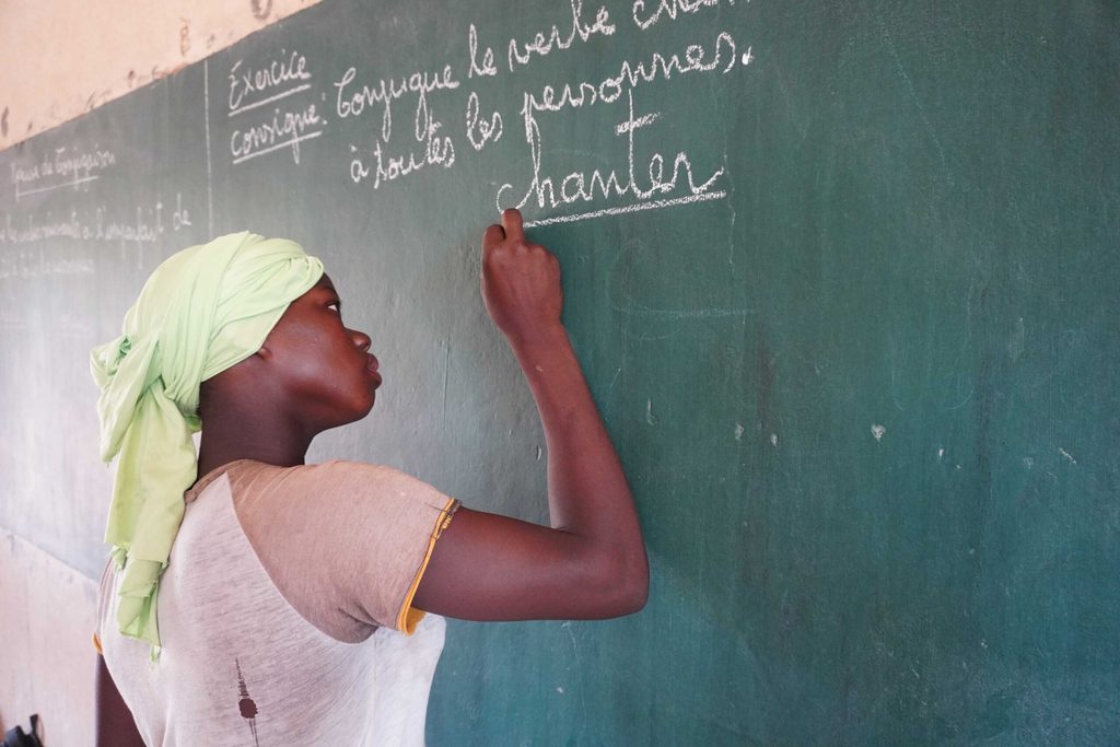 Fatoumata, 14, writing on blackboard