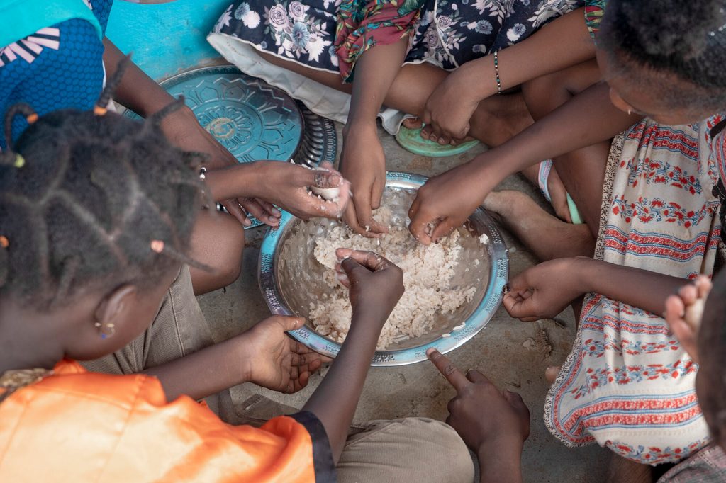 Girls share a bowl of rice at school. 
