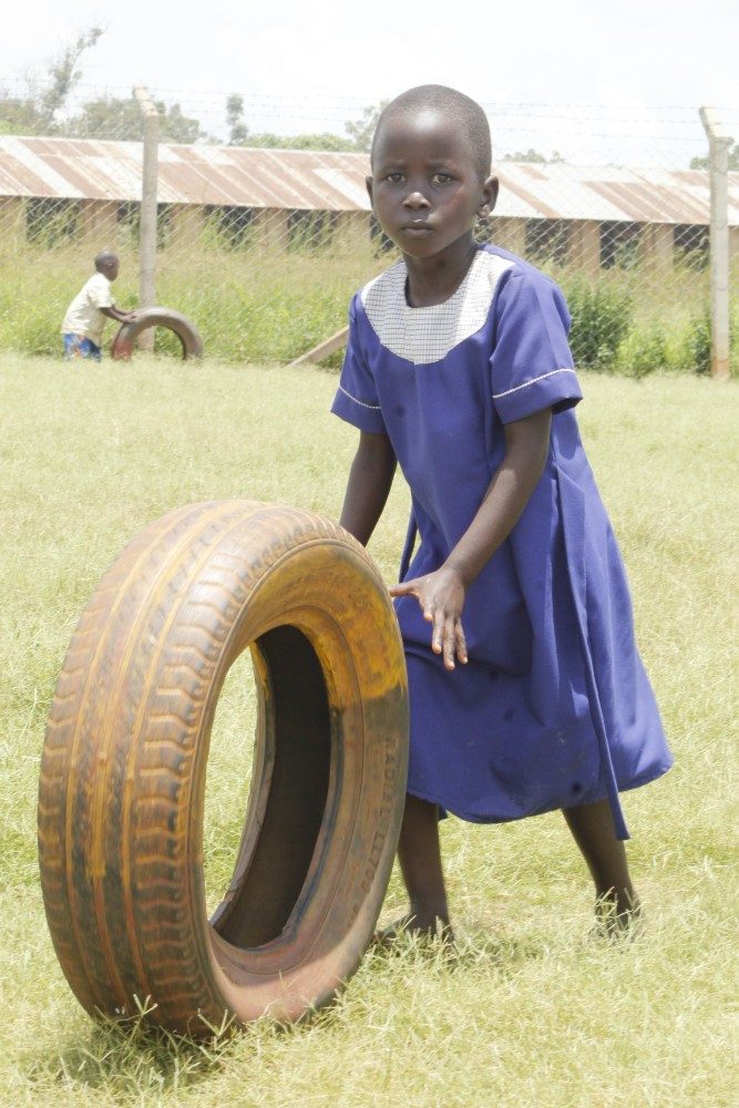 A school girl playing with a tyre in Uganda