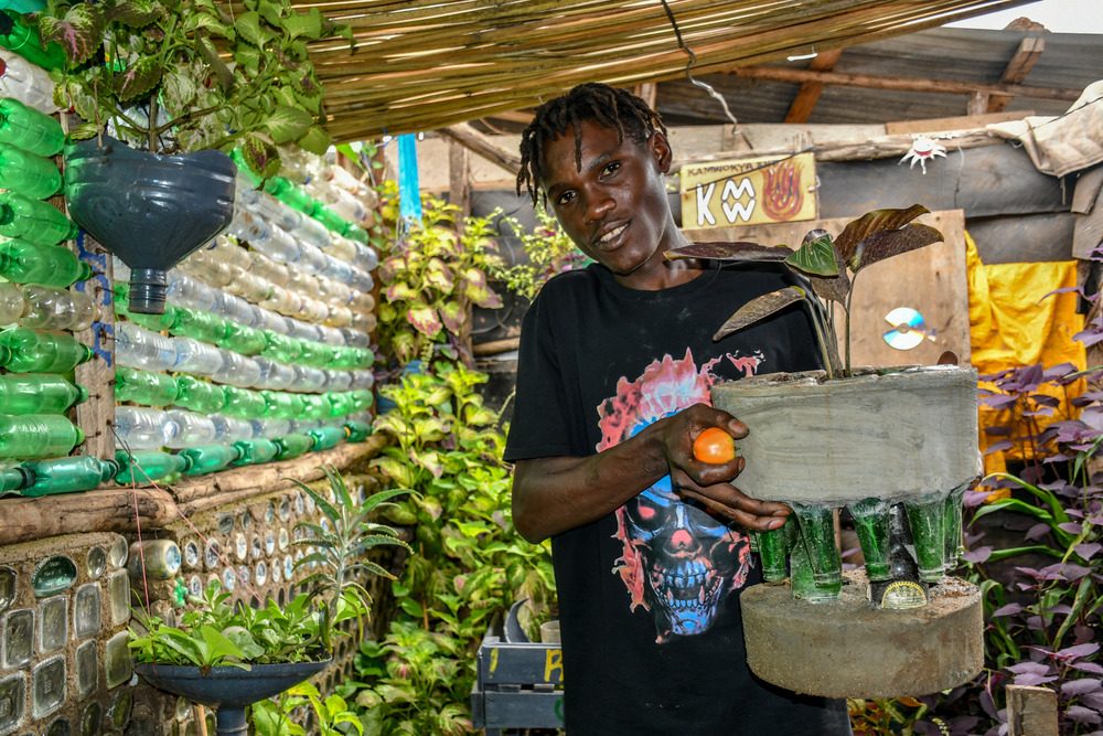 Muhamed holding a flower pot that is made out waste