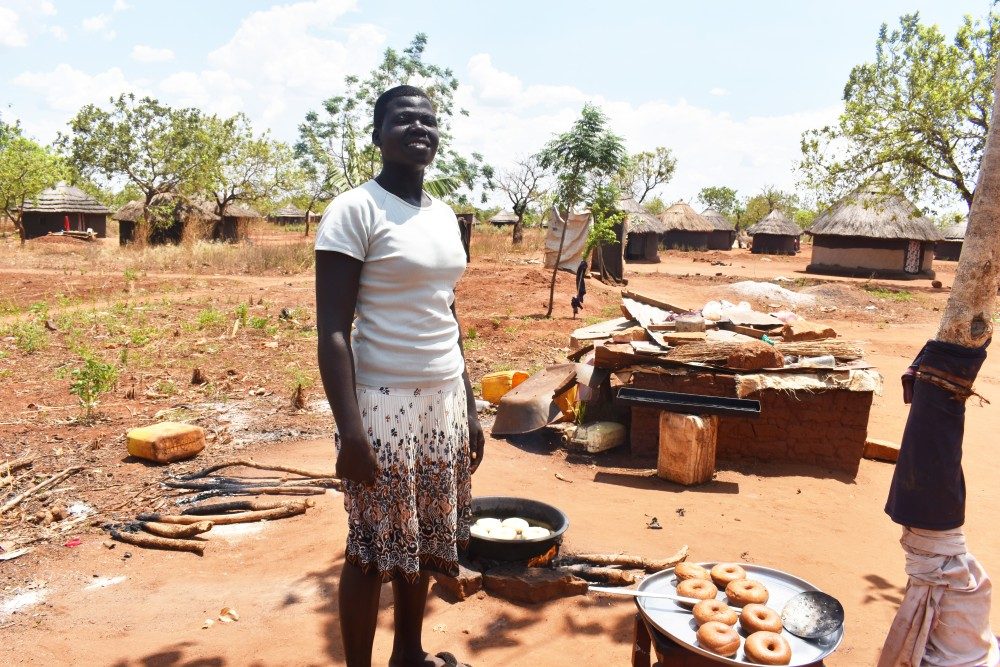 Nancy stands smiling surrounding by breads she has baked. 