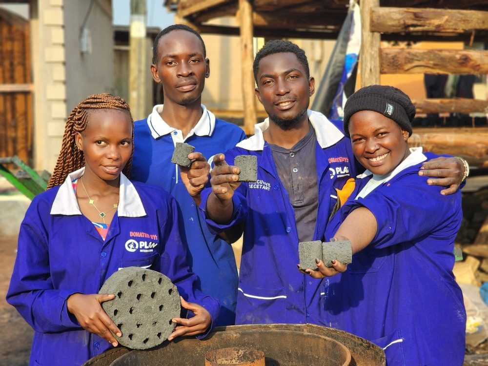 Youth who work making briquettes holding up the birquettes they make.