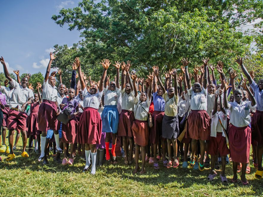 Girls Education club celebrating a competition and throwing their arms up in the air. 