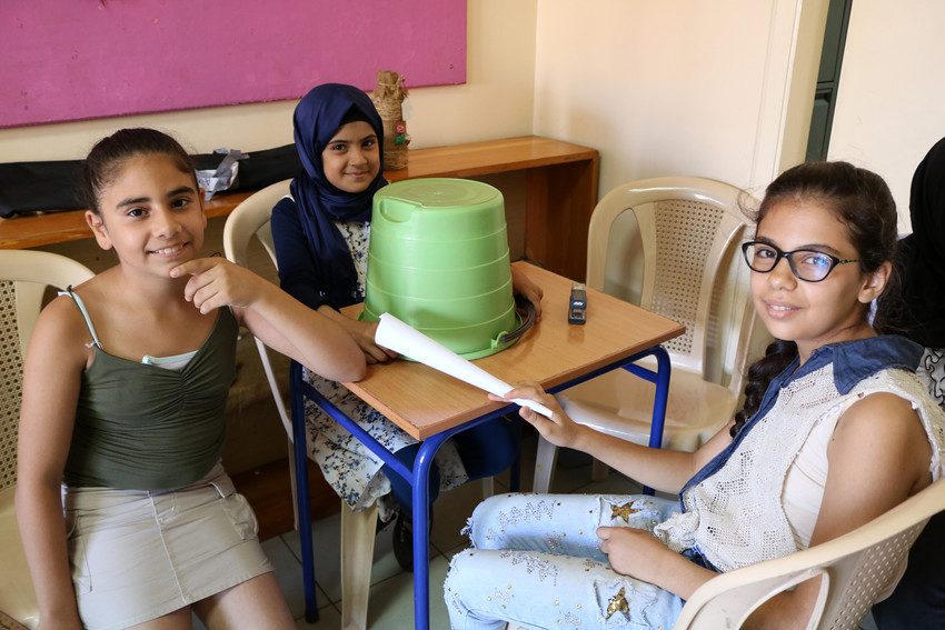 Kholud (centre) and her friends make musical instruments at a Plan International-supported training centre