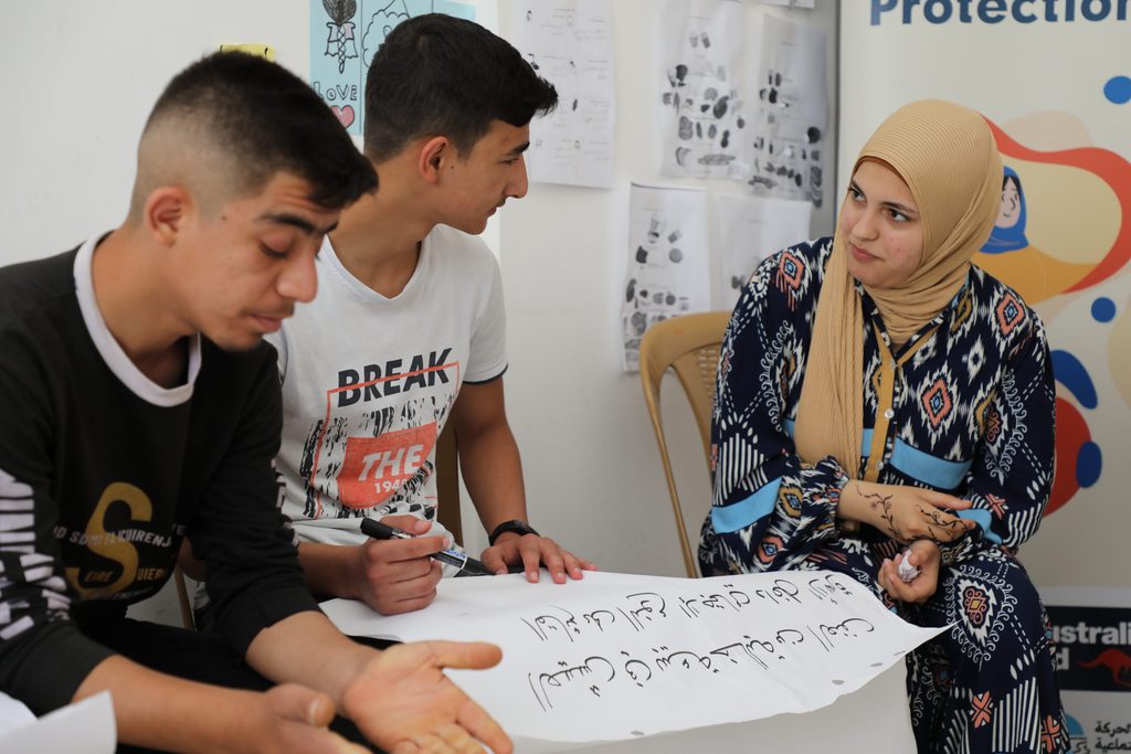a young woman and 2 young men having a discussion