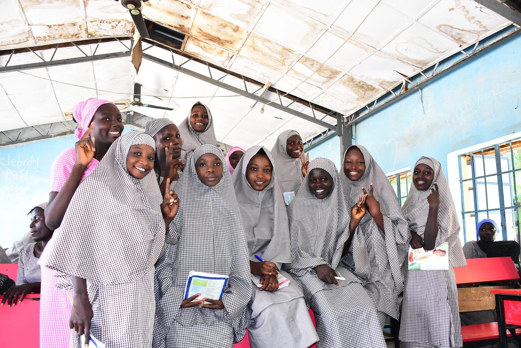 A group of school girls smile at the camera. 