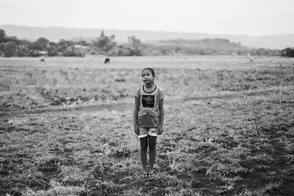 A girl stands in the middle of an open field