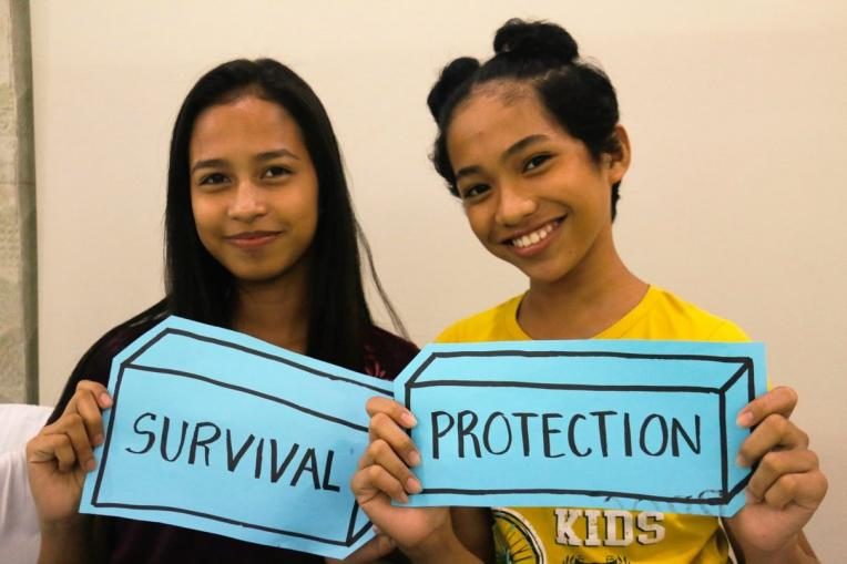Two girls holding up a "Survivor" and "Protection" sign from one of the CAAT Workshops.