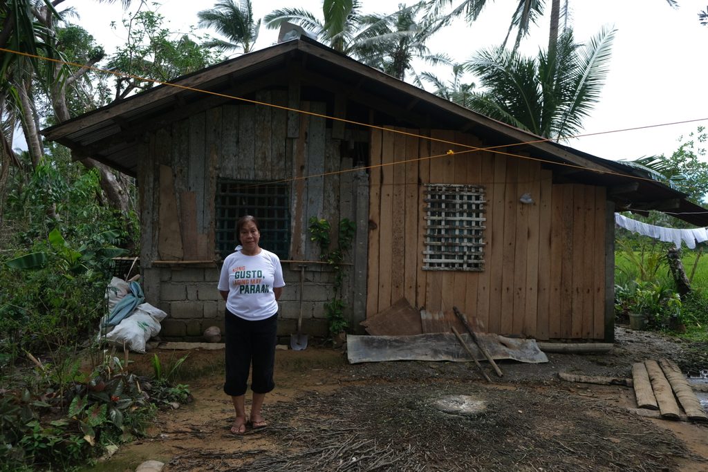 Carmella stands before their home, partially rebuilt after Typhoon Odette.