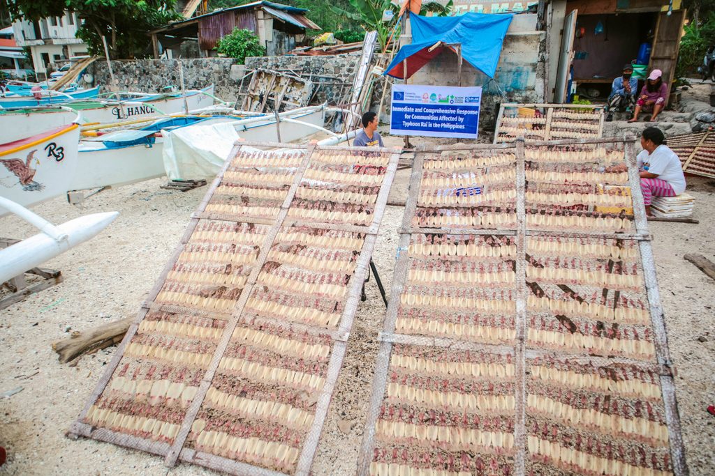 Marina and Marita sit together as they prepare squid for drying