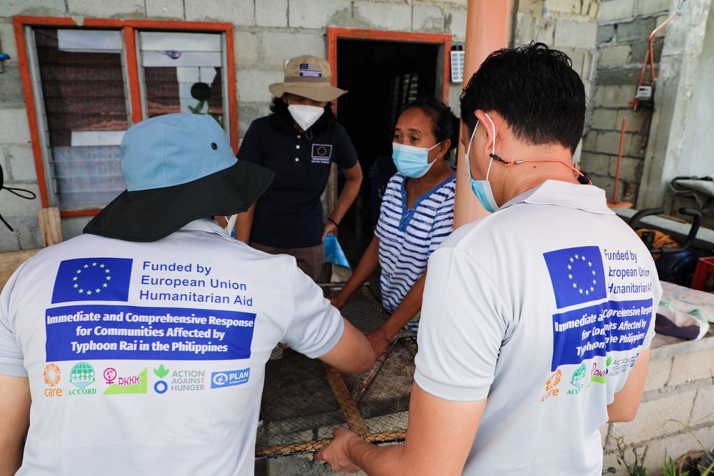 Mercedita shows the netted frames they use to dry squid and fish to Plan International staff during an ECHO monitoring visit 