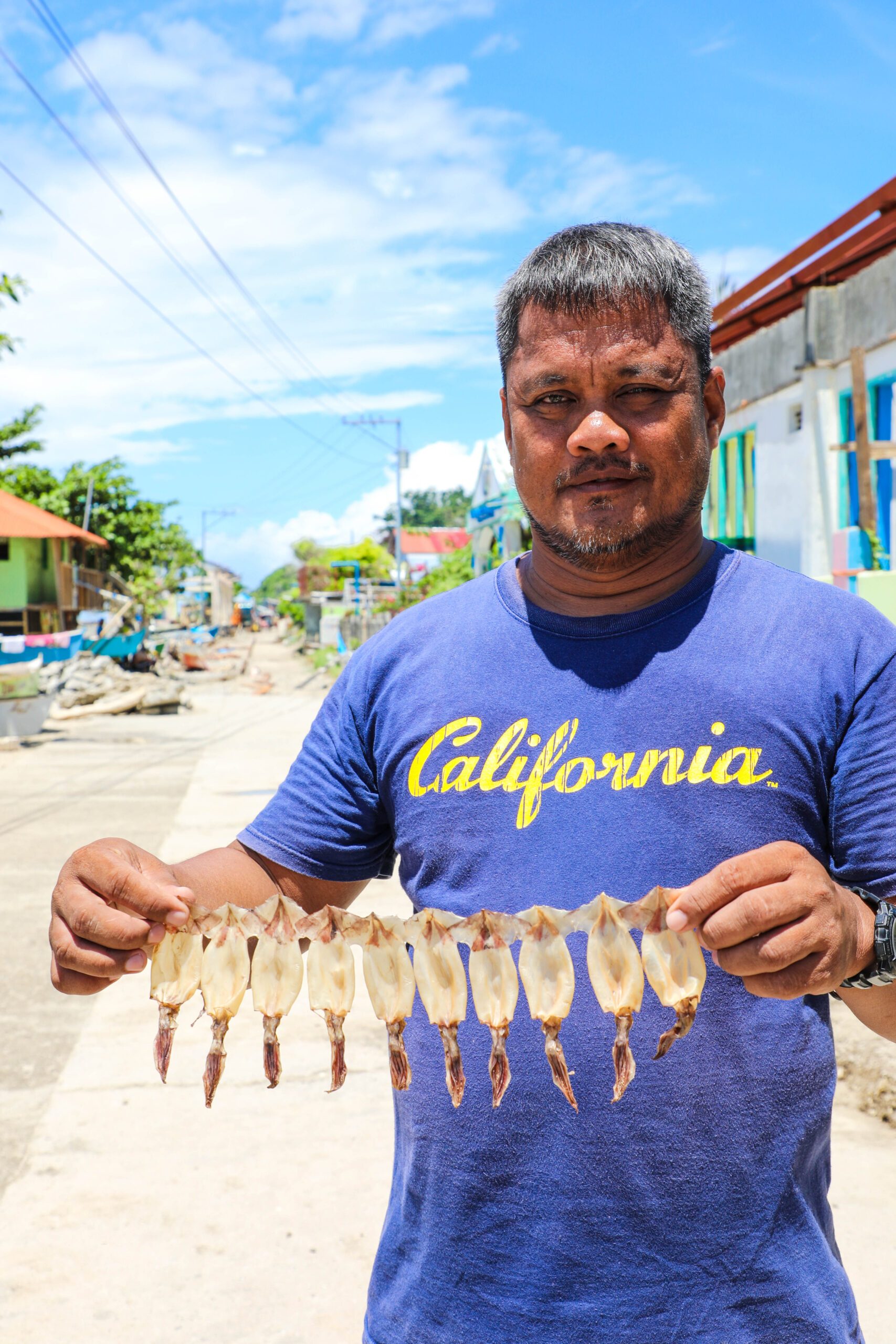 Samuel holds up the dried squid his community members produce