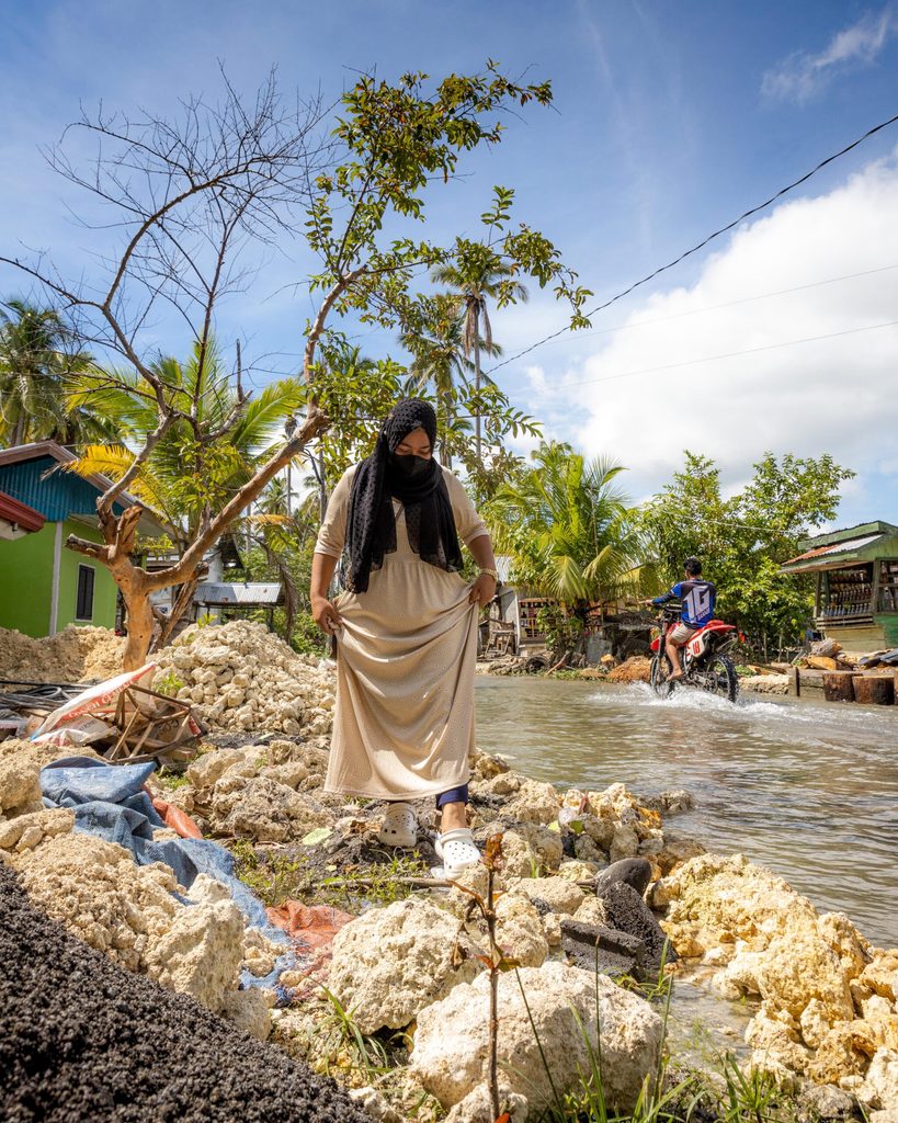 Farhara walks by a flooded street