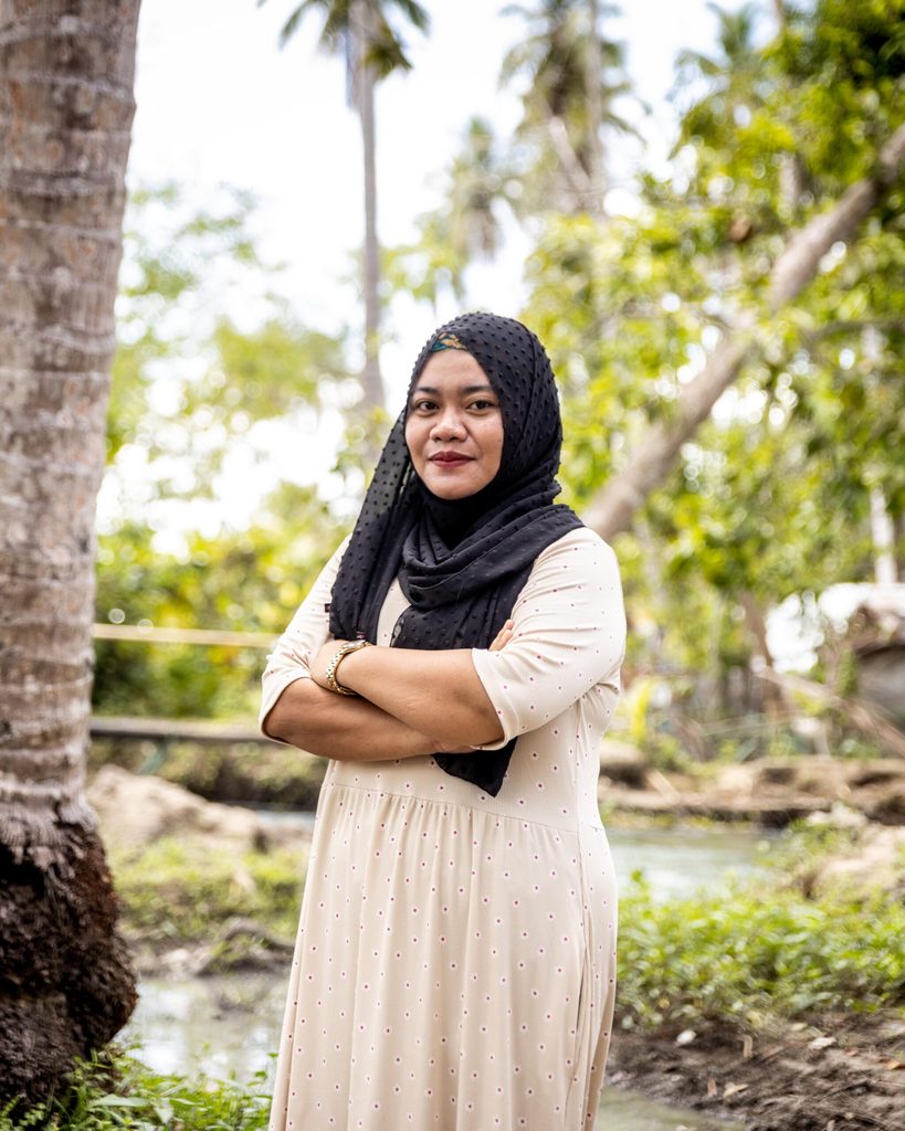 Farhana, 25, poses for a photo by a swamp