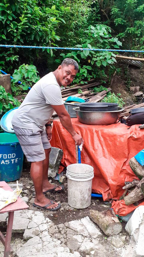 Samuel collects water from one of the faucets connected to the water system 