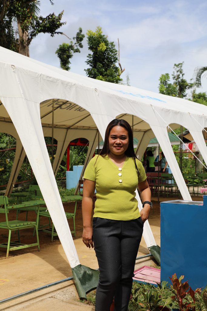 Teacher Dana stands beside the UNICEF Temporary Learning Space (TLS) she uses to conduct classes in the mornings 