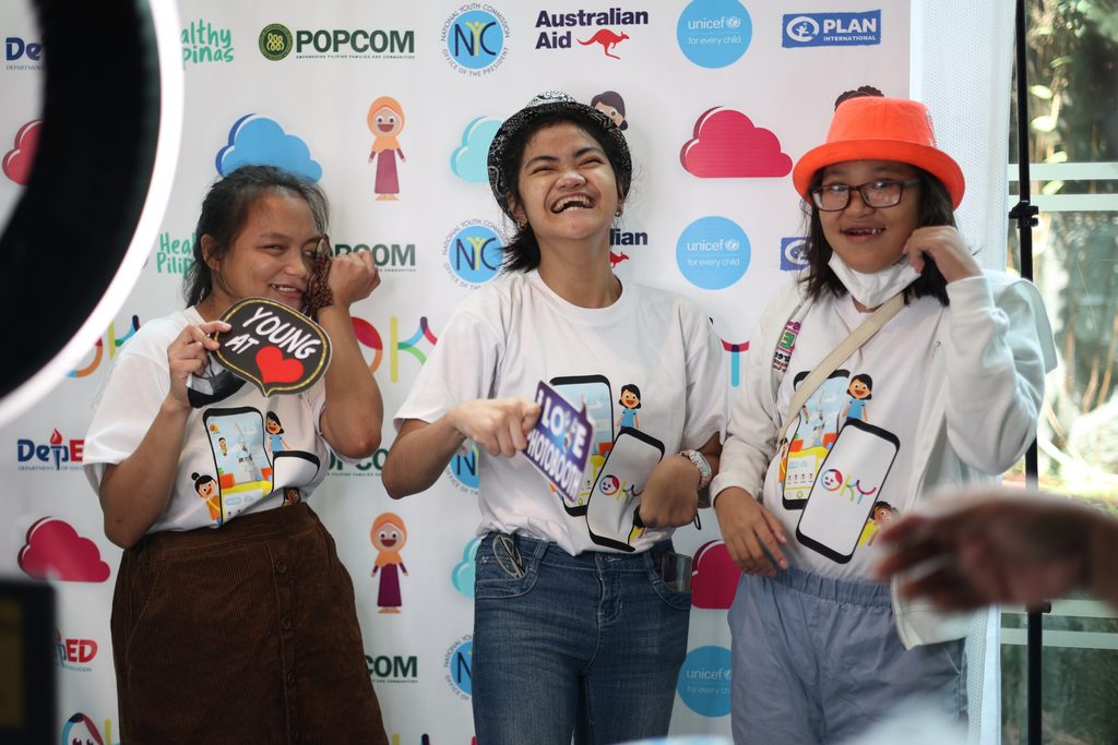 Three girls pose against the photobooth backdrop