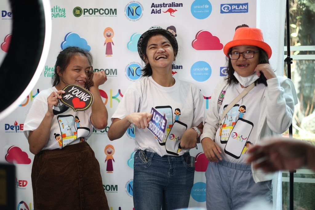 Three girls pose against the photobooth backdrop 