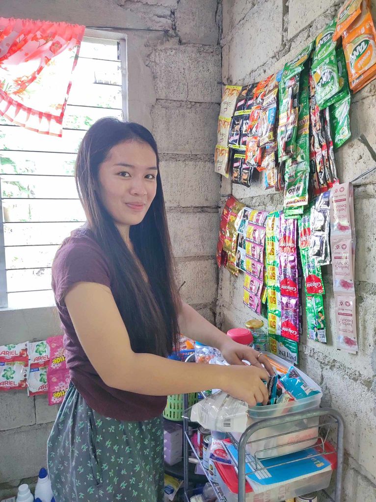 Girl arranging consumer goods in small store