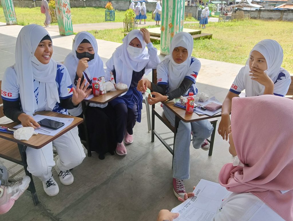 Girls wearing hijabs are gathered in a huddle