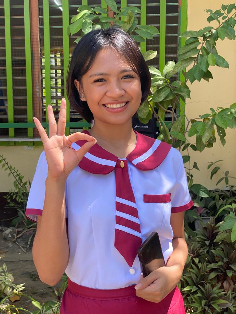 Girl poses for the camera doing an "okay" hand gesture