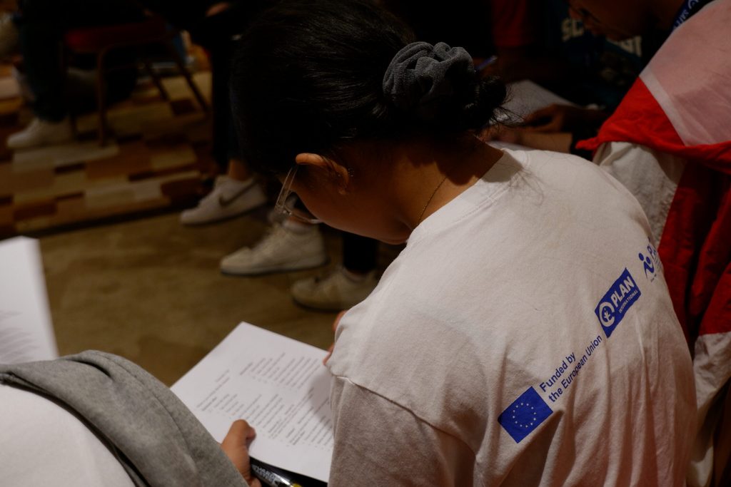 A young woman fills up a form on paper during a workshop.