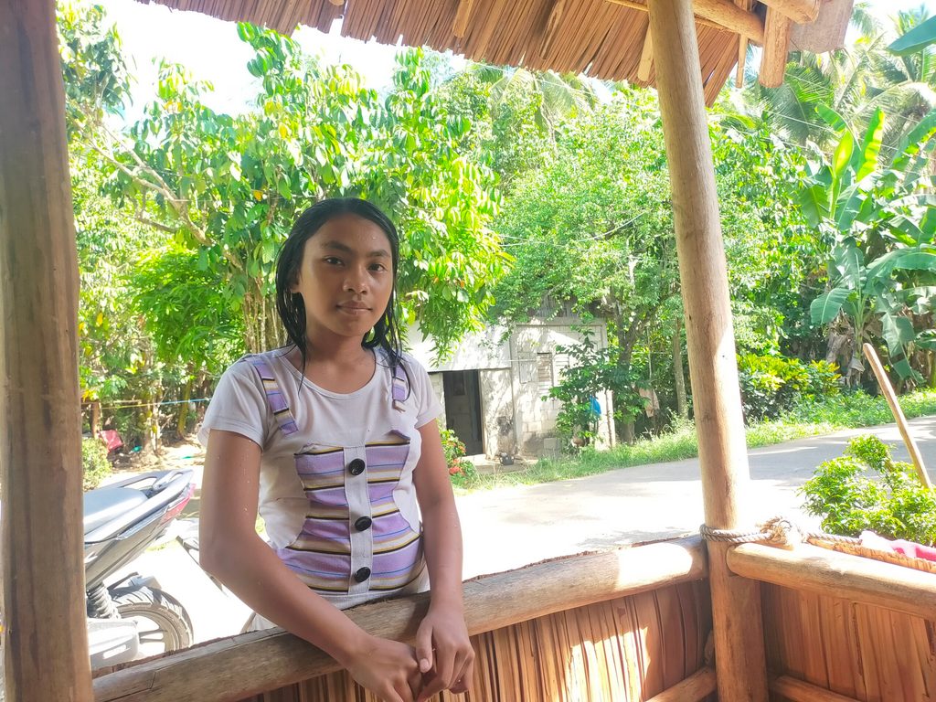 A young girl stands outside a cabana