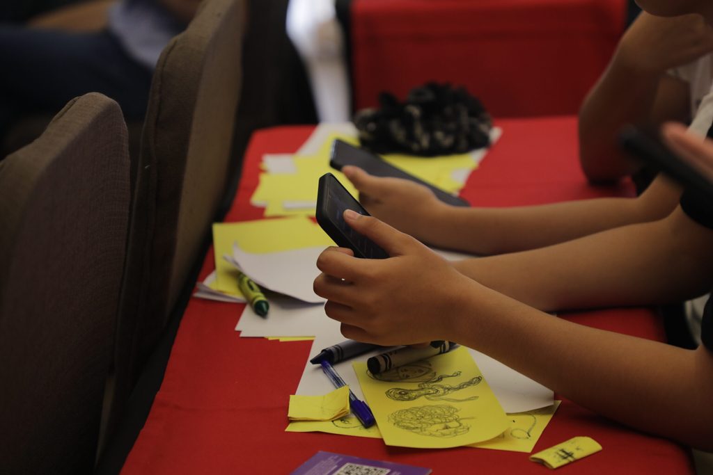 A group of young people browse on their smartphones during a workshop.