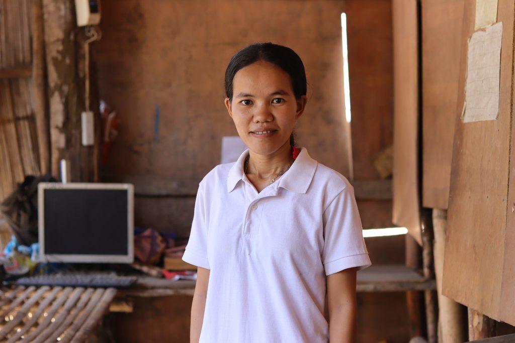 Young woman wearing a white shirt poses for a photo inside her home