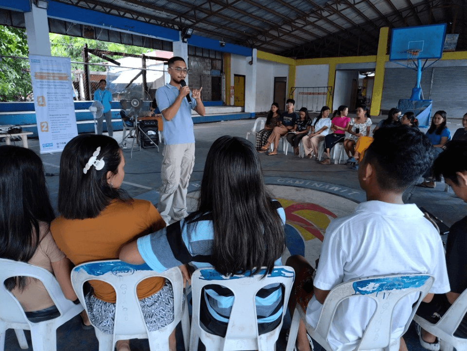 A photo of a boy facilitating a discussion among fellow youth.