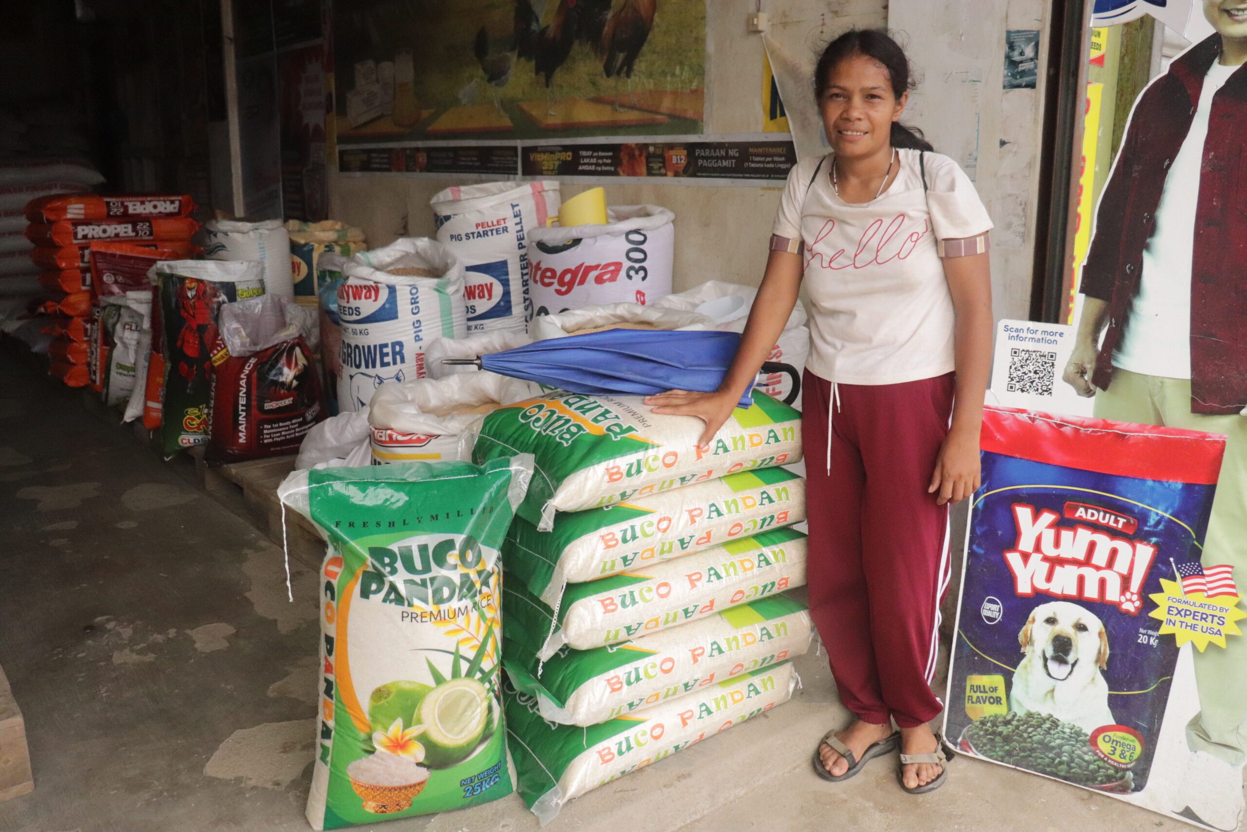 A woman standing beside bags of rice she purchased.