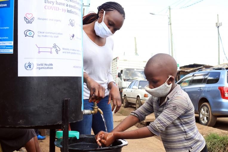 Lornah helps child wash his hands at one of the handwashing stations in Kibera
