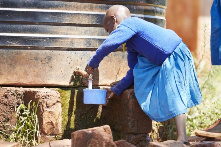 A school girl collects water from one of the tanks installed by Plan International