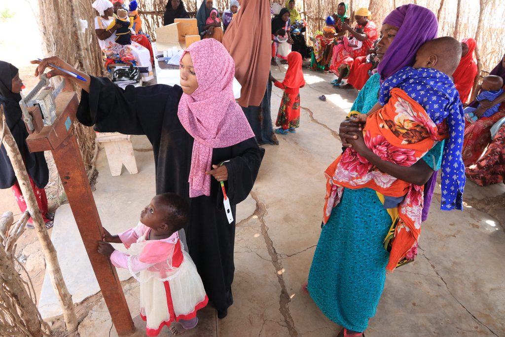 Health worker, Mwanadie Hakofa attending to a mother and her children at a local dispensary