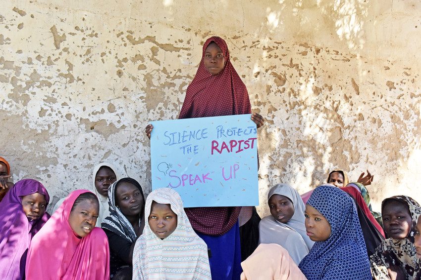 A girl holding up a banner calling for people to speak out about rape