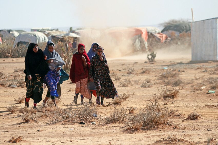 Group of displaced girls and young women from displacement camp in Somalia walk across the arid land