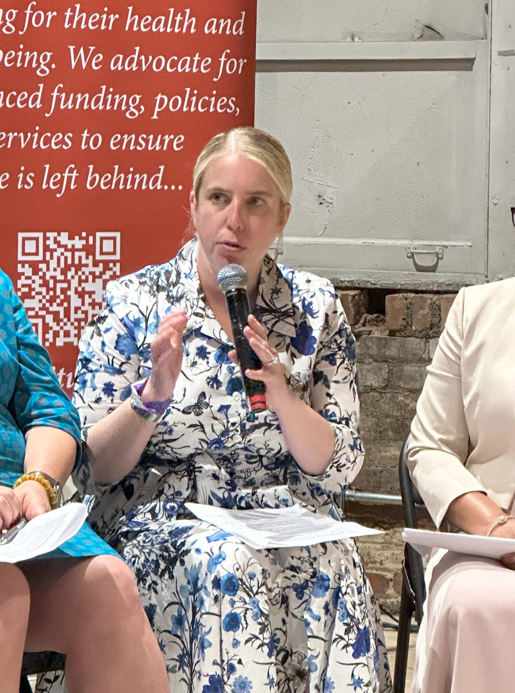 A woman speaks into a microphone at an event