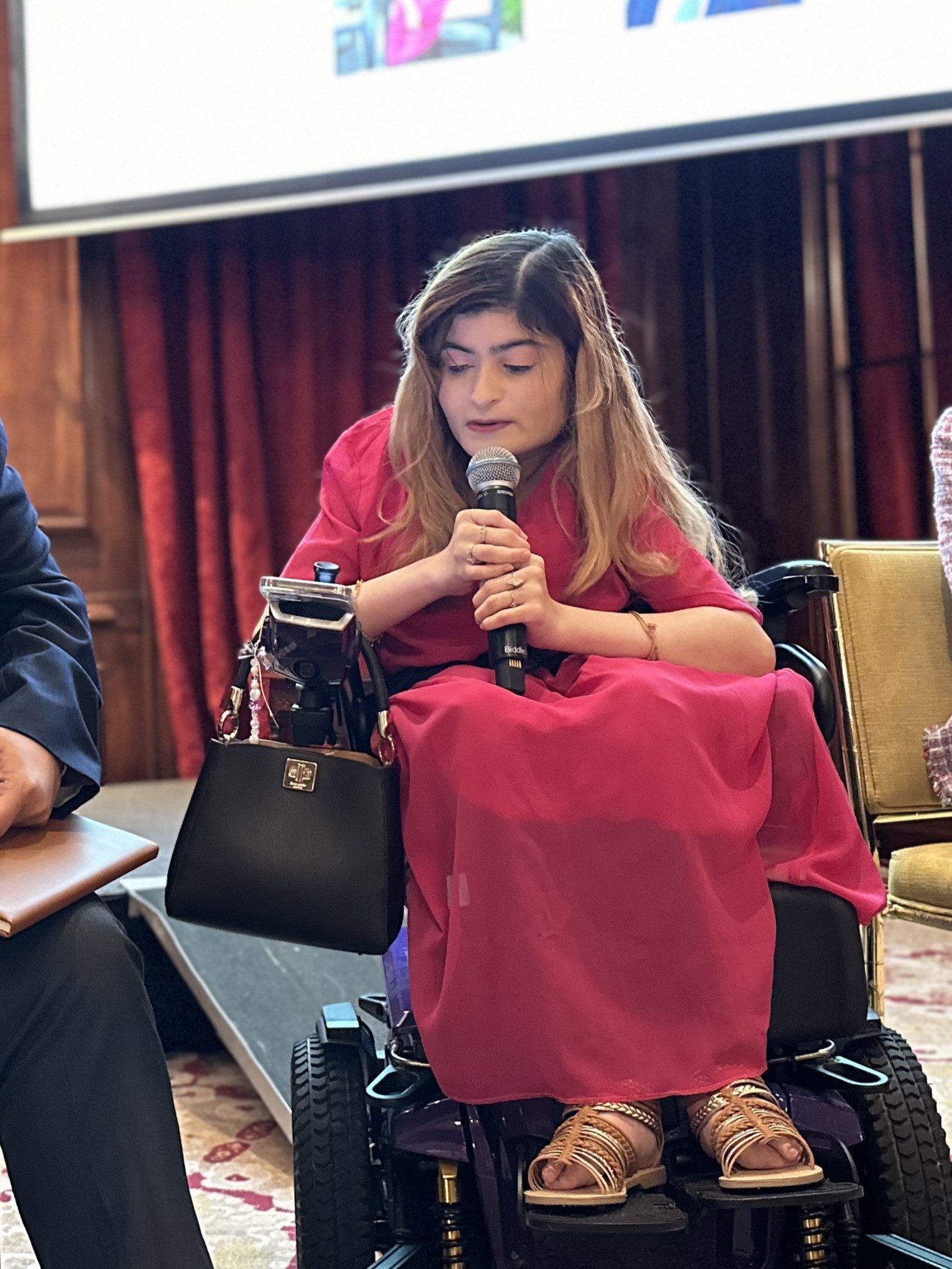 A woman speaks into a microphone at an event.