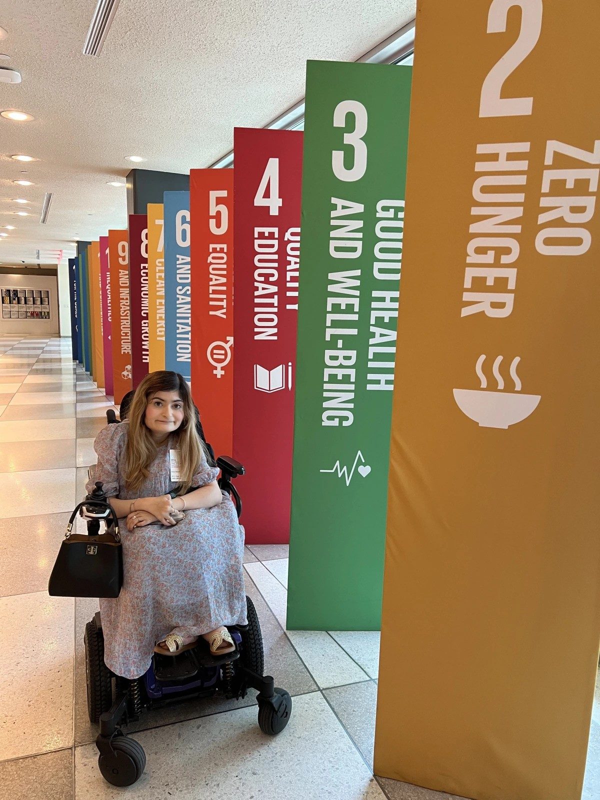 Marya, a youth advocate, poses in front of SDG banners.