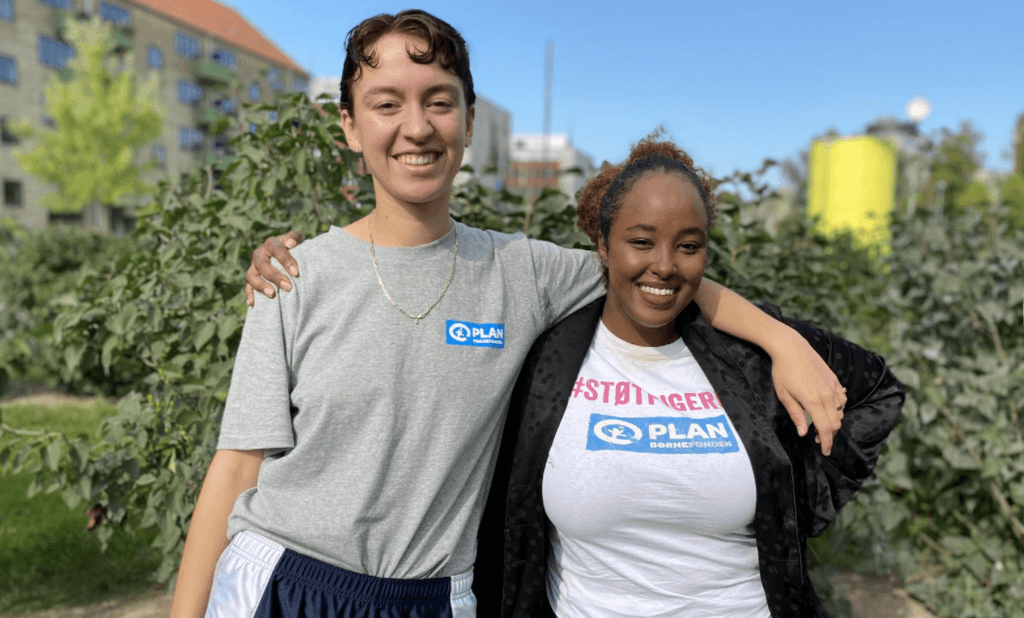 Two persons standing together smiling.