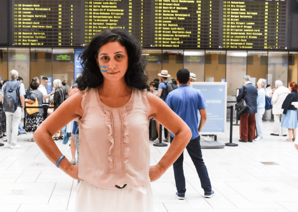 Woman standing in front of train schedule board.