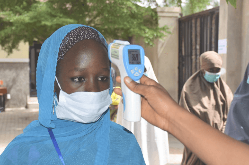 Girl taking her temperature with a thermometer.